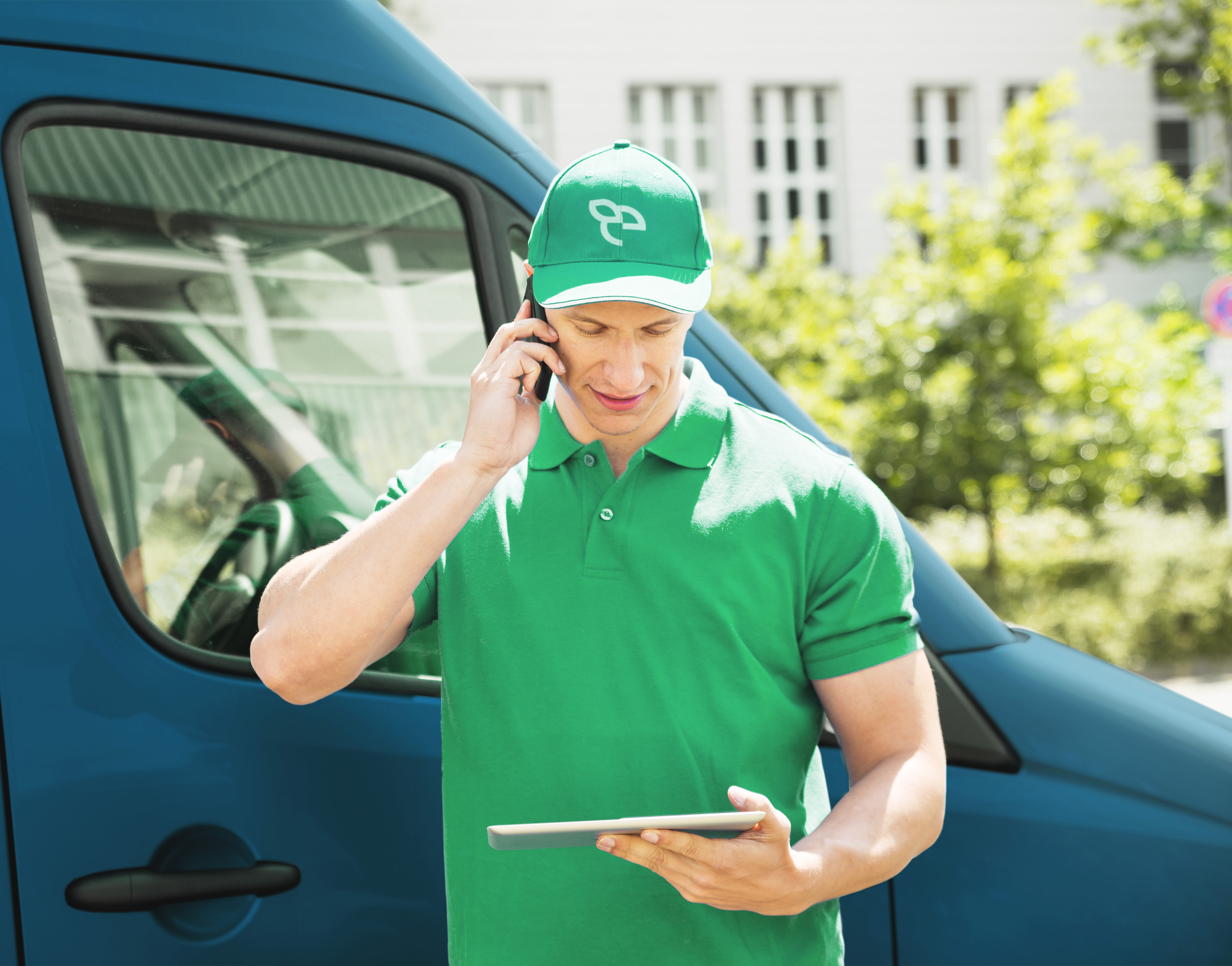 Livreur Ecolise qui téléphone en tenant une tablette devant un camion de livraison